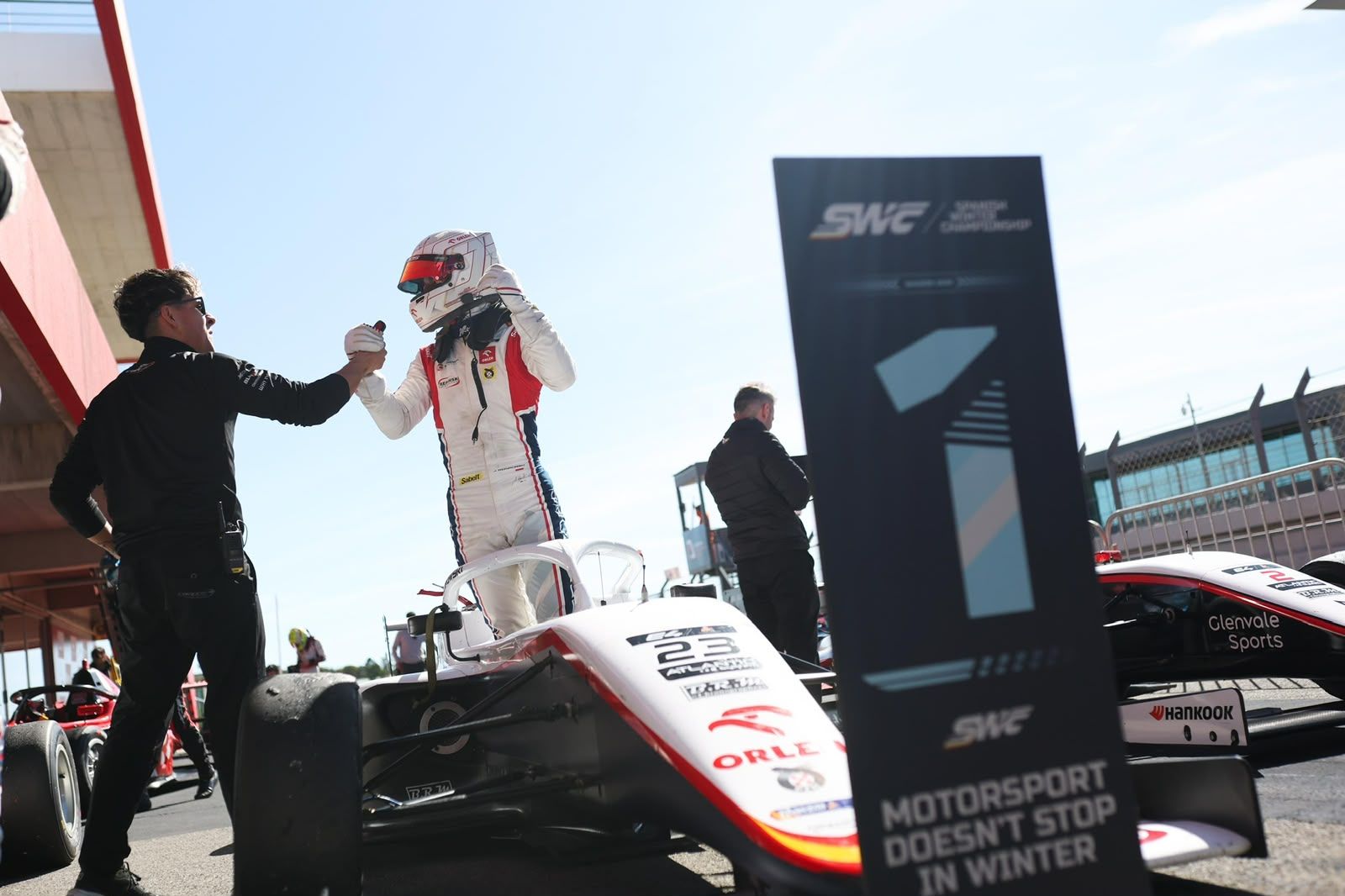 Driver and mechanic celebrating next to the P1 board at parc fermé