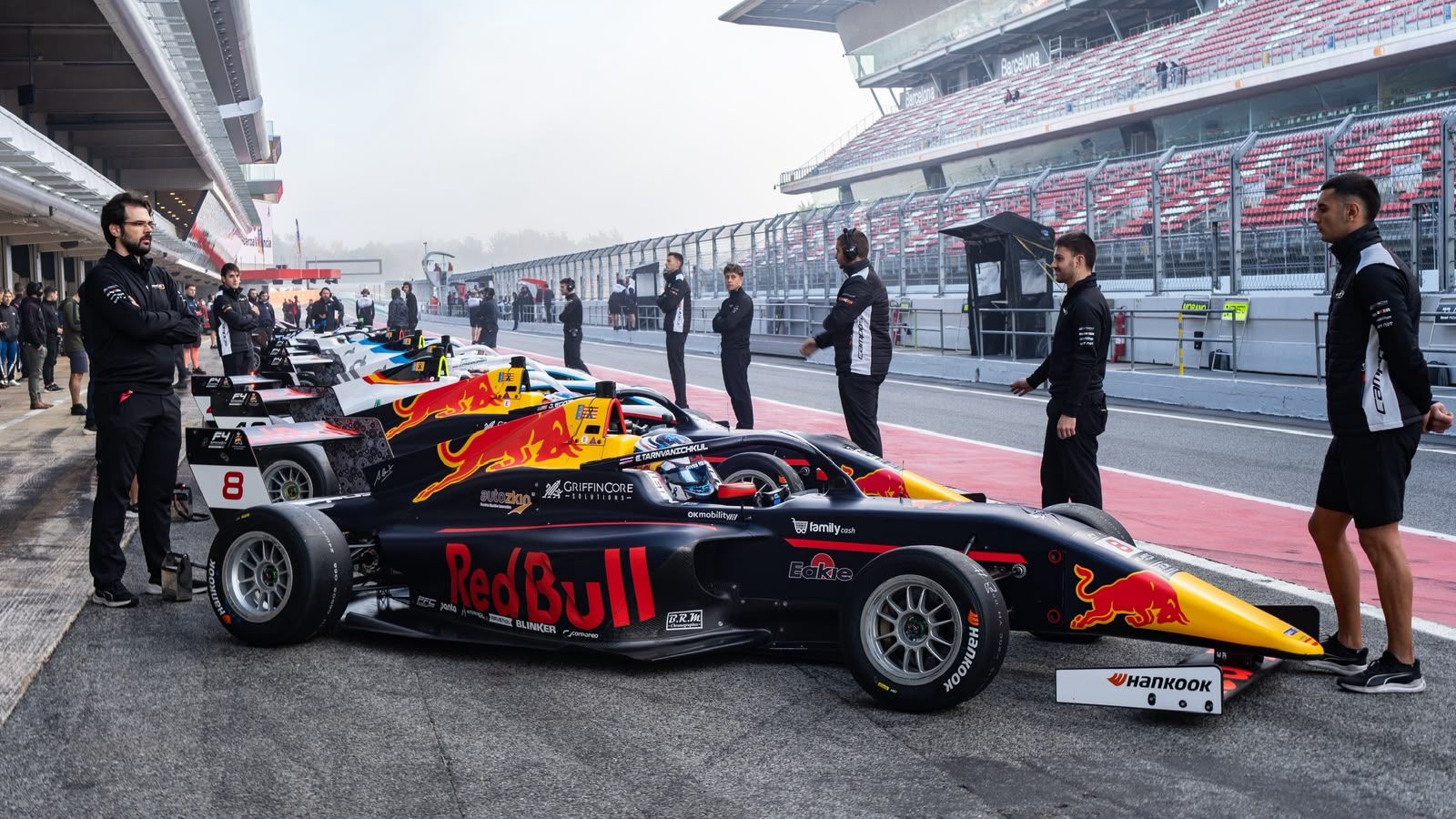 Single-seater rolling through the pit lane with mechanics around it